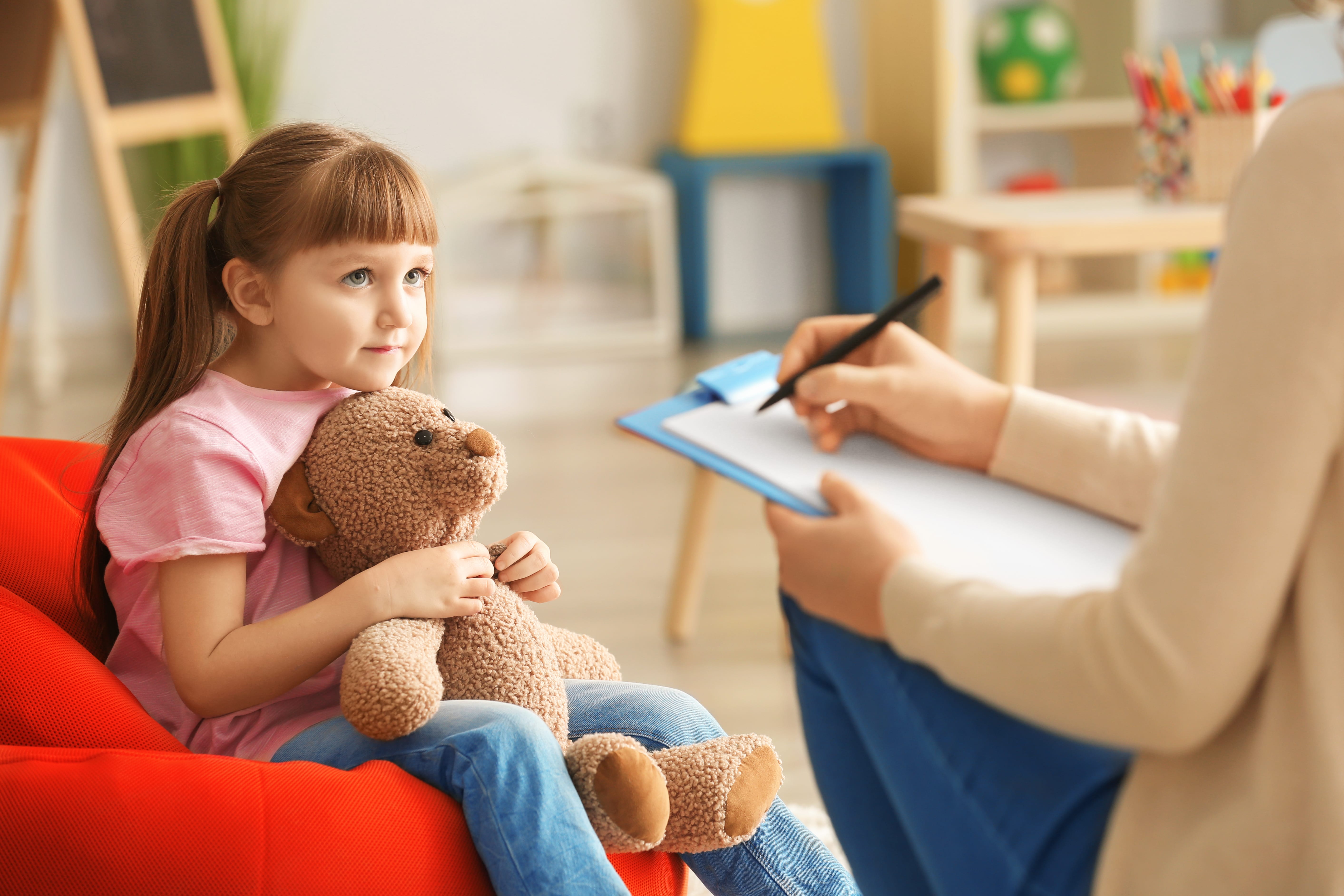 Little girl with her teddy talking to a psychologist